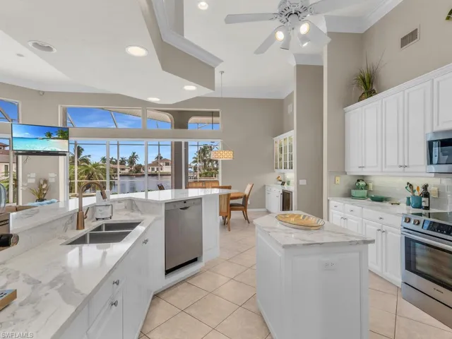 Kitchen featuring white cabinetry, ceiling fan, sink, a center island, and appliances with stainless steel finishes
