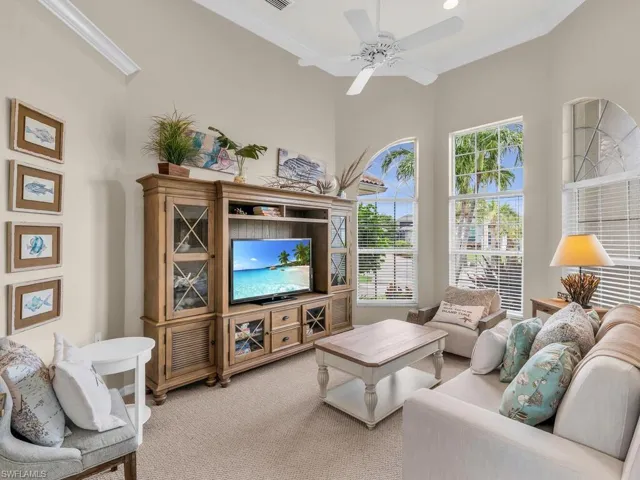 Carpeted living room with ornamental molding, ceiling fan, a wealth of natural light, and a towering ceiling