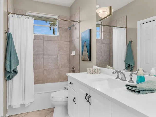 Full bathroom featuring shower / tub combo, tile patterned floors, toilet, and vanity