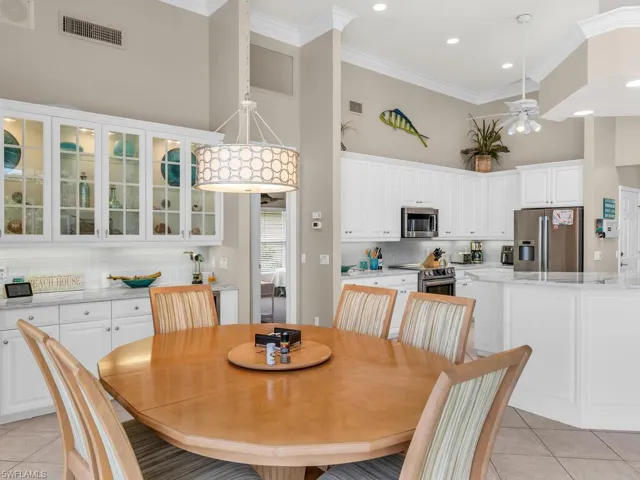 Dining room with light tile patterned flooring, a high ceiling, crown molding, and ceiling fan