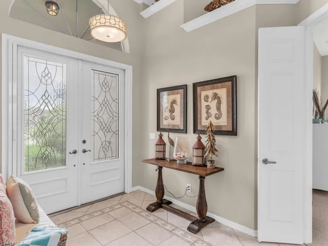 Foyer featuring light tile patterned flooring, crown molding, and french doors