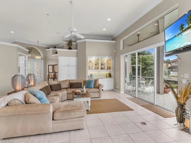 Living room featuring crown molding, ceiling fan, and light tile patterned floors
