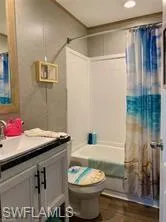 Full bathroom featuring shower / bath combination with curtain, vanity, and toilet