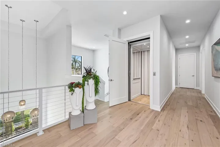 Corridor with light wood-style flooring, recessed lighting, and elevator