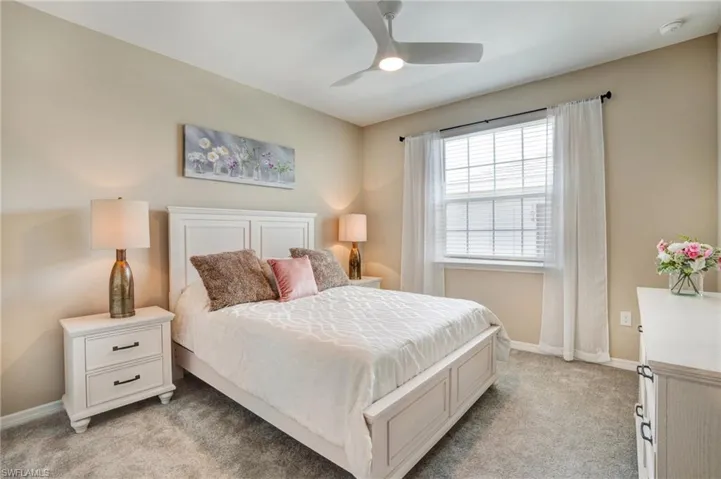 Bedroom featuring light carpet, baseboards, and a ceiling fan