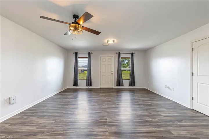 Unfurnished room with dark wood-style flooring and ceiling fan