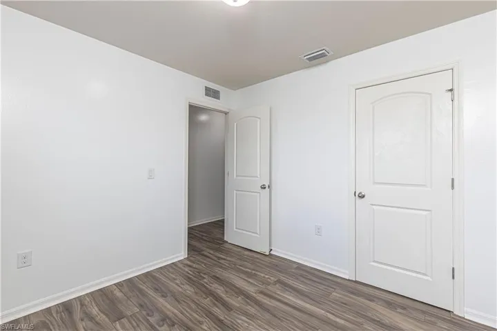 Unfurnished bedroom with dark wood-style floors and baseboards