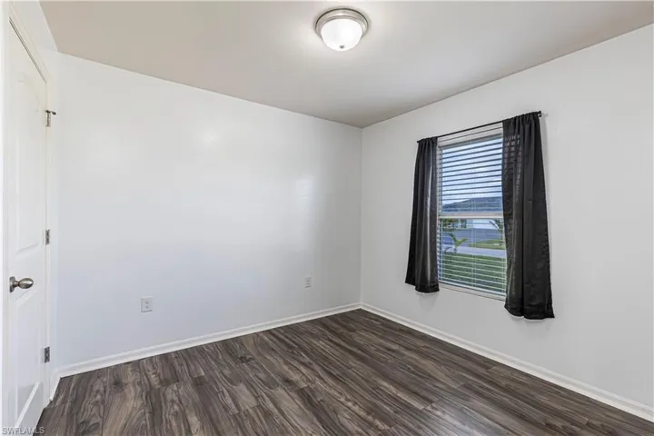 Unfurnished room with dark wood-style flooring and baseboards