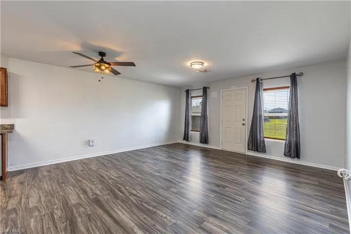 Unfurnished living room with dark wood-style flooring and a ceiling fan