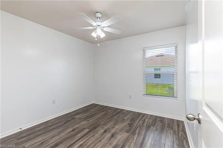 Spare room with dark wood-style flooring and ceiling fan
