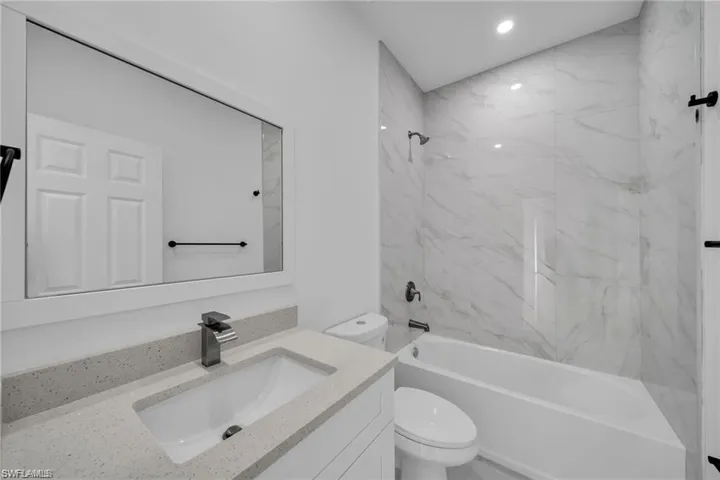 Modern bathroom featuring a single vanity with a light-toned countertop, an integrated rectangular sink, and a framed mirror