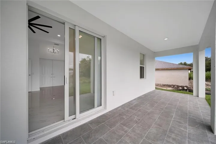 Expansive covered patio featuring large format grey tile flooring and recessed lighting