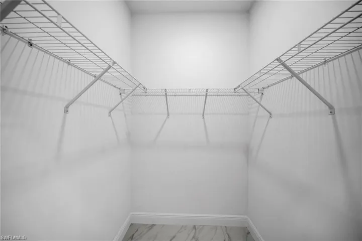 Walk-in closet featuring white wire shelving, white painted walls, and light-colored flooring with a subtle pattern