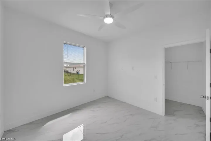 Room featuring a ceiling fan with integrated lighting, wood-finish flooring, and a window with white trim