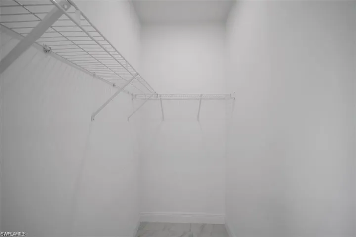 Closet featuring white wire shelving, matching hanging rod, white walls, and light-toned flooring