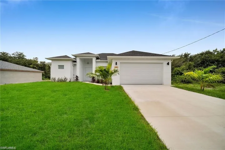 Contemporary white stucco exterior with an attached garage, covered entry, front landscaping, and a concrete driveway