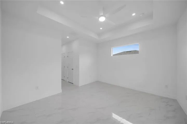 Spacious interior room featuring white tile flooring, white baseboards, and white walls