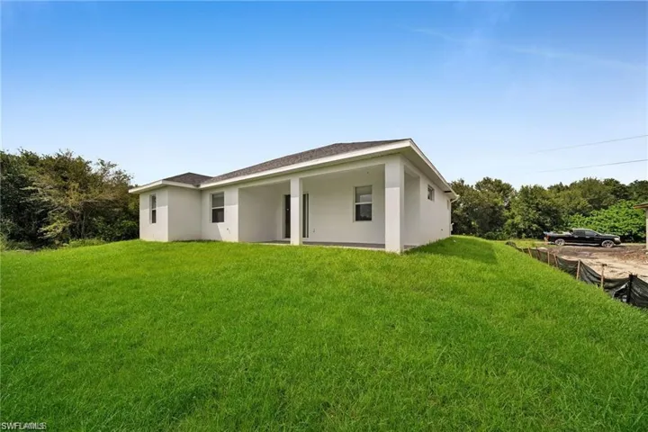 Exterior featuring a stucco finish, covered patio, dark shingle roofing, and a manicured lawn