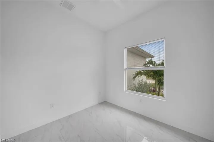 Room featuring white walls, white baseboards, and large format tile flooring with a subtle veining pattern