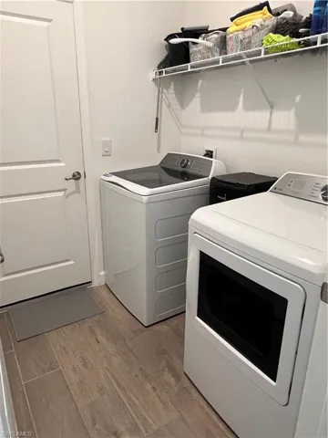 Washroom with light wood finished floors and washing machine and dryer