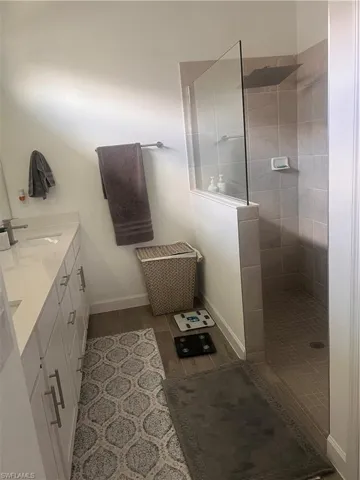 Bathroom featuring double vanity, walk in shower, and wood finish floors