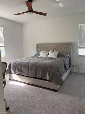 Carpeted bedroom with a ceiling fan and baseboards