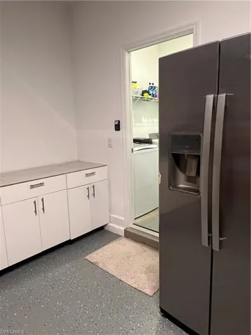 Kitchen with refrigerator, white cabinets, light countertops, and range