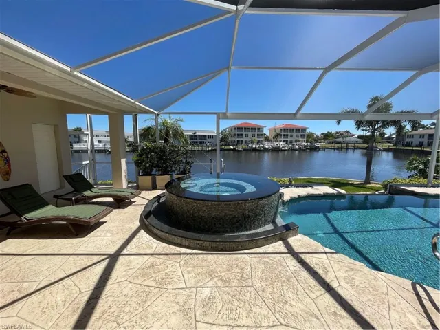 View of patio / terrace with ceiling fan, a water view, a lanai, and a pool with connected hot tub