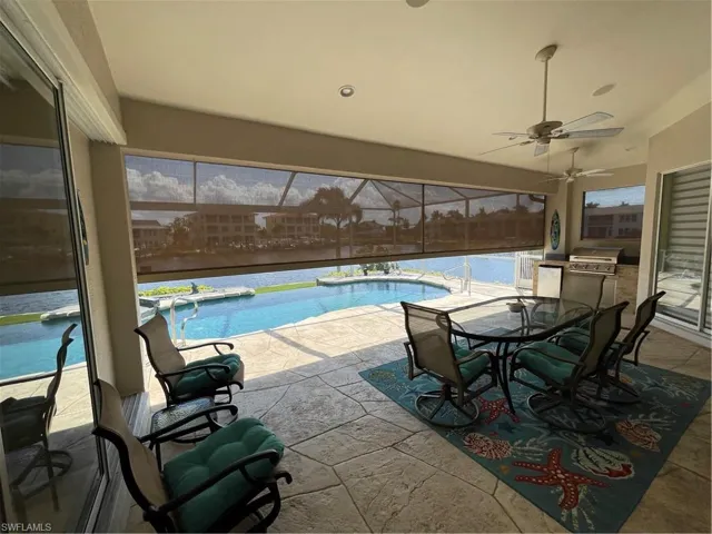 Pool featuring area for grilling, outdoor dining space, a ceiling fan, a patio, and glass enclosure
