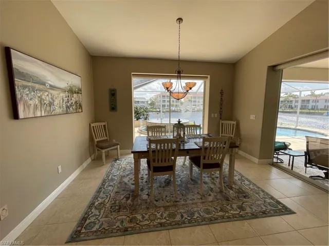 Dining space with an inviting chandelier, light tile patterned floors, and a healthy amount of sunlight