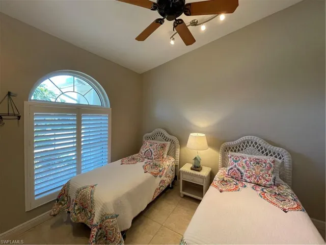 Den currently used as a bedroom featuring light tile patterned floors, plantation shades, ceiling fan, and lofted ceiling