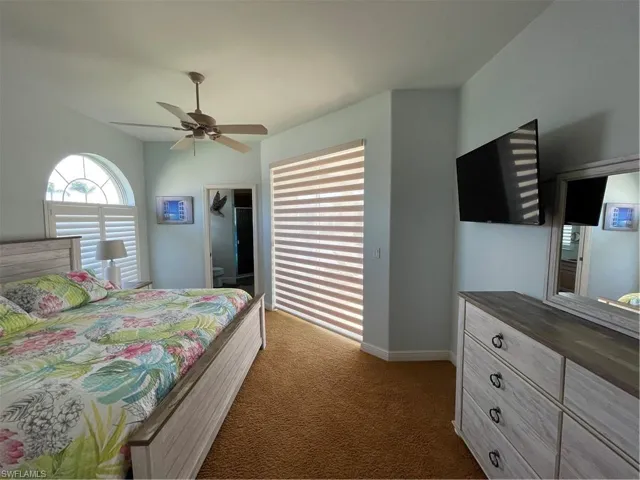 Bedroom second master with ceiling fan, baseboards, and dark colored carpet