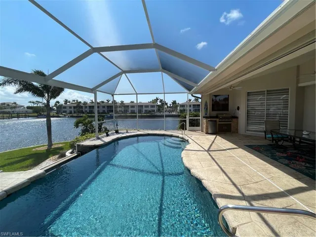 Outdoor pool featuring glass enclosure, a patio area, and a water view