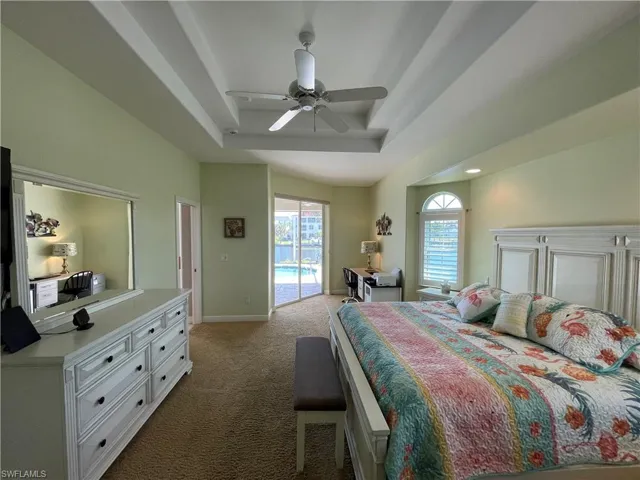 Bedroom with a tray ceiling, multiple windows, carpet flooring, and access to exterior