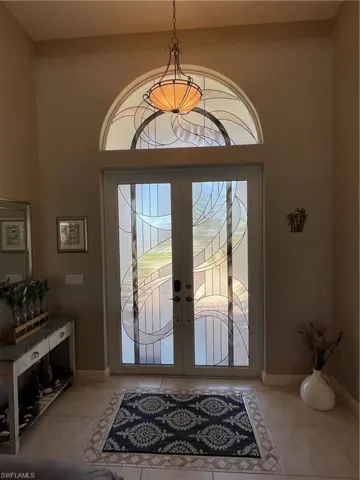 Entrance foyer featuring light tile patterned flooring, french doors, and baseboards