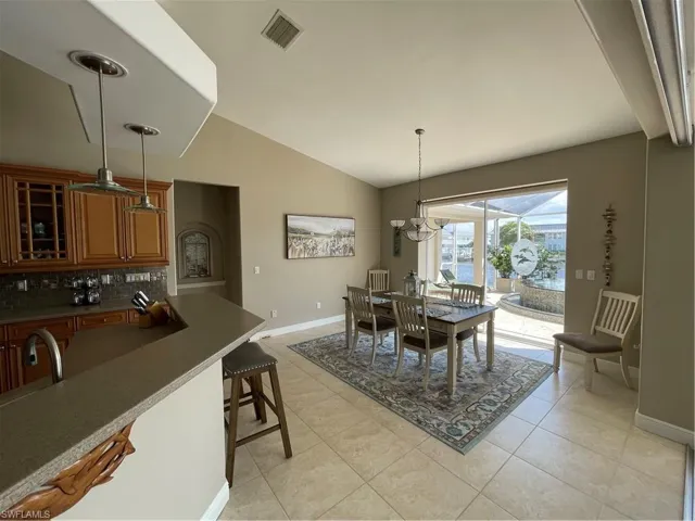 Dining space featuring baseboards, visible vents, lofted ceiling, light tile patterned flooring, and a chandelier