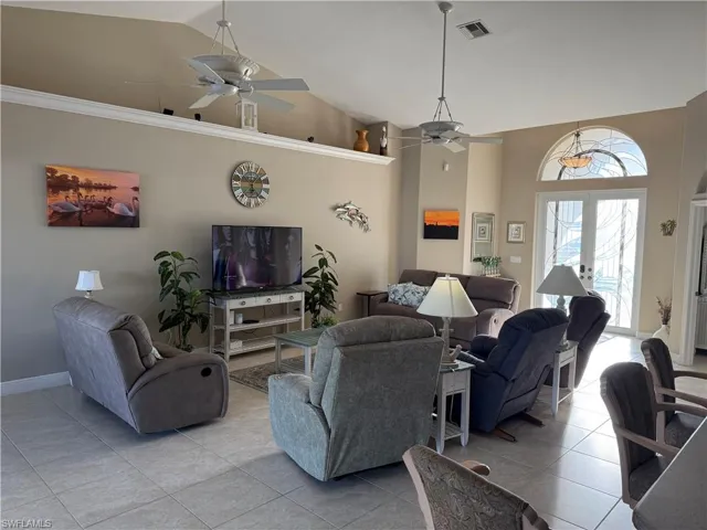 Living room featuring light tile patterned floors, visible vents, high vaulted ceiling, and ceiling fan