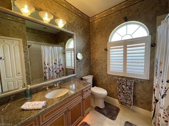 Bathroom featuring vanity, a shower with curtain, baseboards, wallpapered walls, and toilet