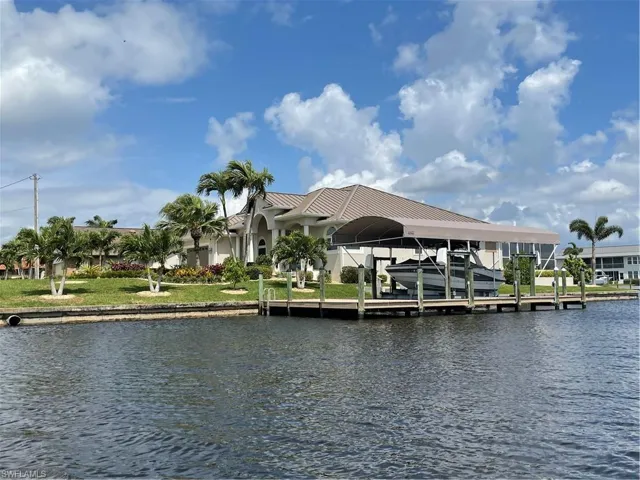 View of dock featuring boat lift, a lawn, and a water view