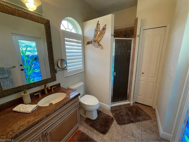 Second master Bathroom featuring baseboards, toilet, a stall shower, and vanity