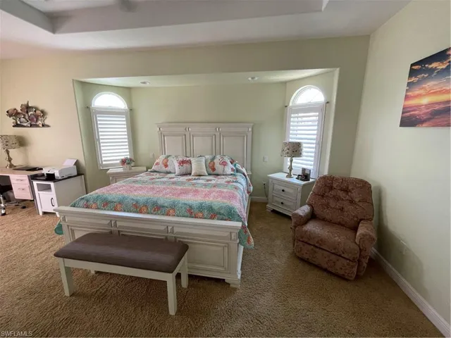 Carpeted bedroom with multiple windows and baseboards