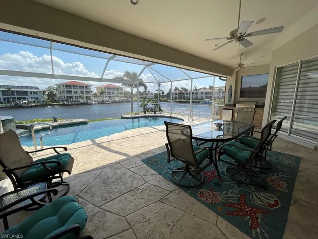 Outdoor pool featuring a water view, a patio, a lanai, outdoor dining area, and ceiling fan