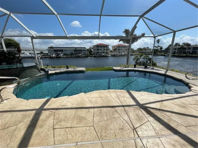 Outdoor pool featuring glass enclosure, a water view, and a patio