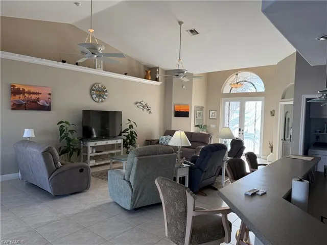 Living area with light tile patterned floors, visible vents, high vaulted ceiling, and ceiling fan