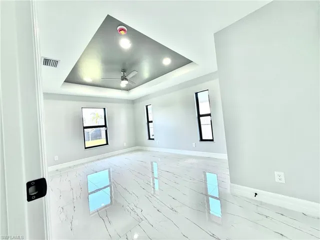 Spare room with healthy amount of natural light, light marble finish floors, ceiling fan, and recessed lighting