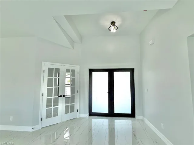 Entryway with french doors, marble look tile flooring, and a high ceiling