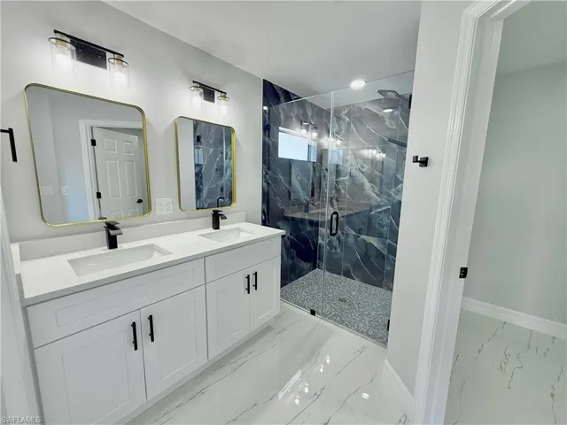Full bathroom with a marble finish shower and double vanity