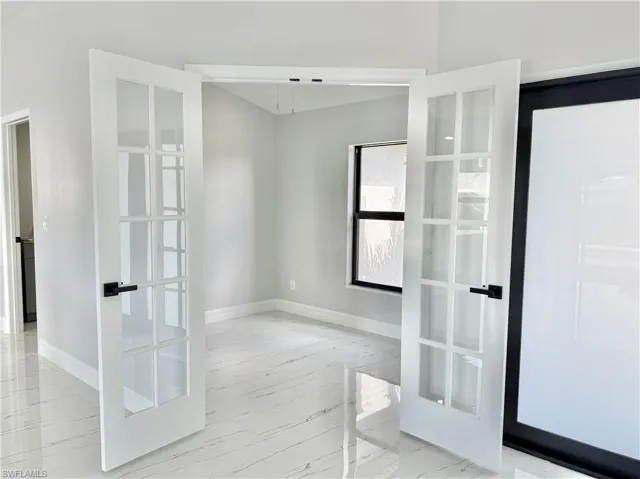 Unfurnished room with light marble finish flooring and french doors