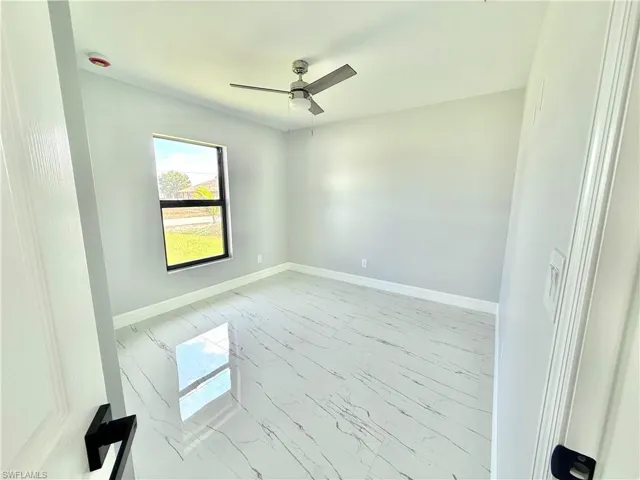 Empty room with light marble finish floors and ceiling fan