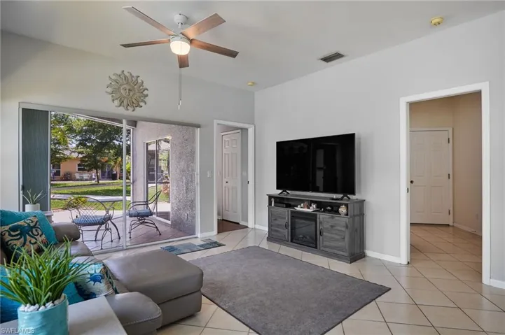 Living room featuring light tile patterned floors, a ceiling fan, and vaulted ceiling